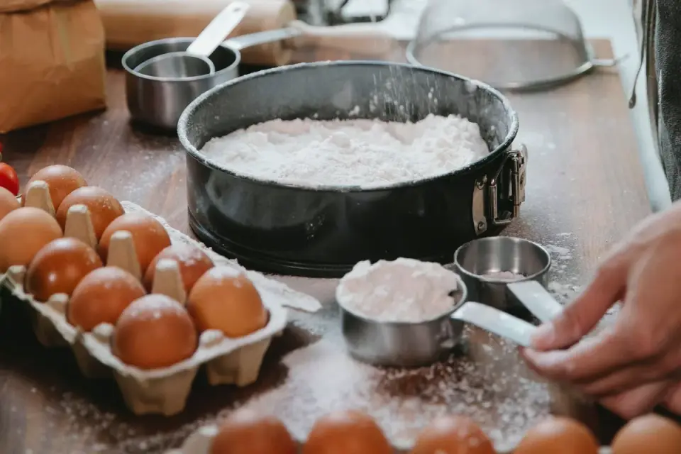 A hand measuring fiber powder with a small teaspoon over a dog&#x27;s food bowl