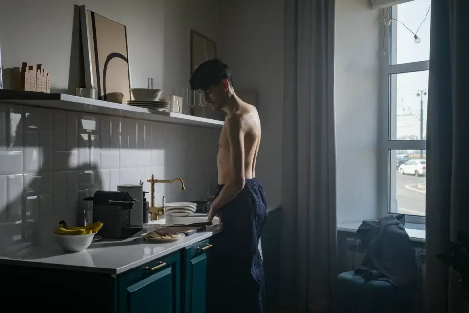 A medium-sized dog eating from a bowl in a sunlit kitchen