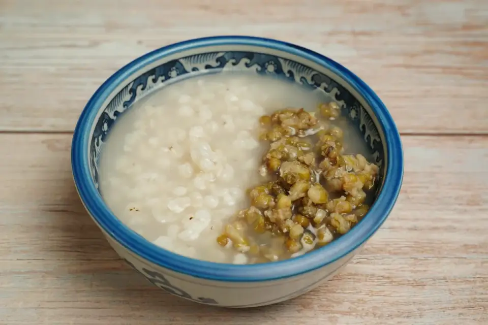 A small white bowl of rice water beside a portion of plain cooked white rice