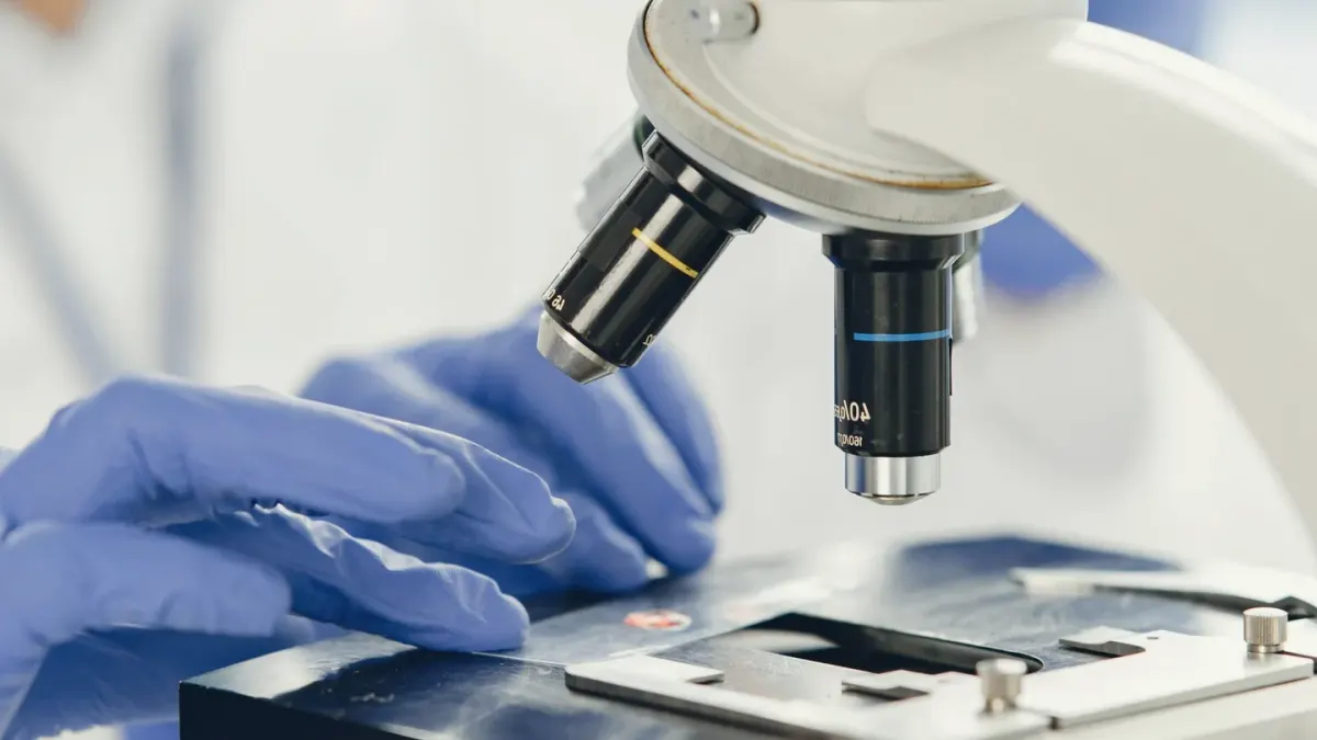 A veterinarian in a lab coat reviewing a fecal sample slide next to a dog