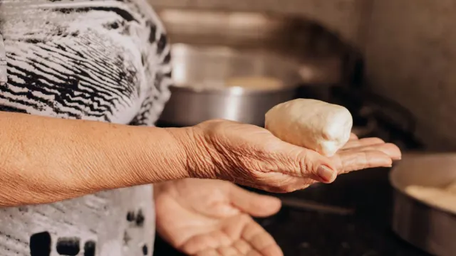 An owner offering a soft chew supplement to a graying senior dog at the kitchen counter
