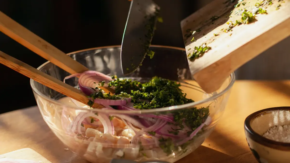 Sliced onions on a wooden cutting board with a dog's stainless steel bowl in the background