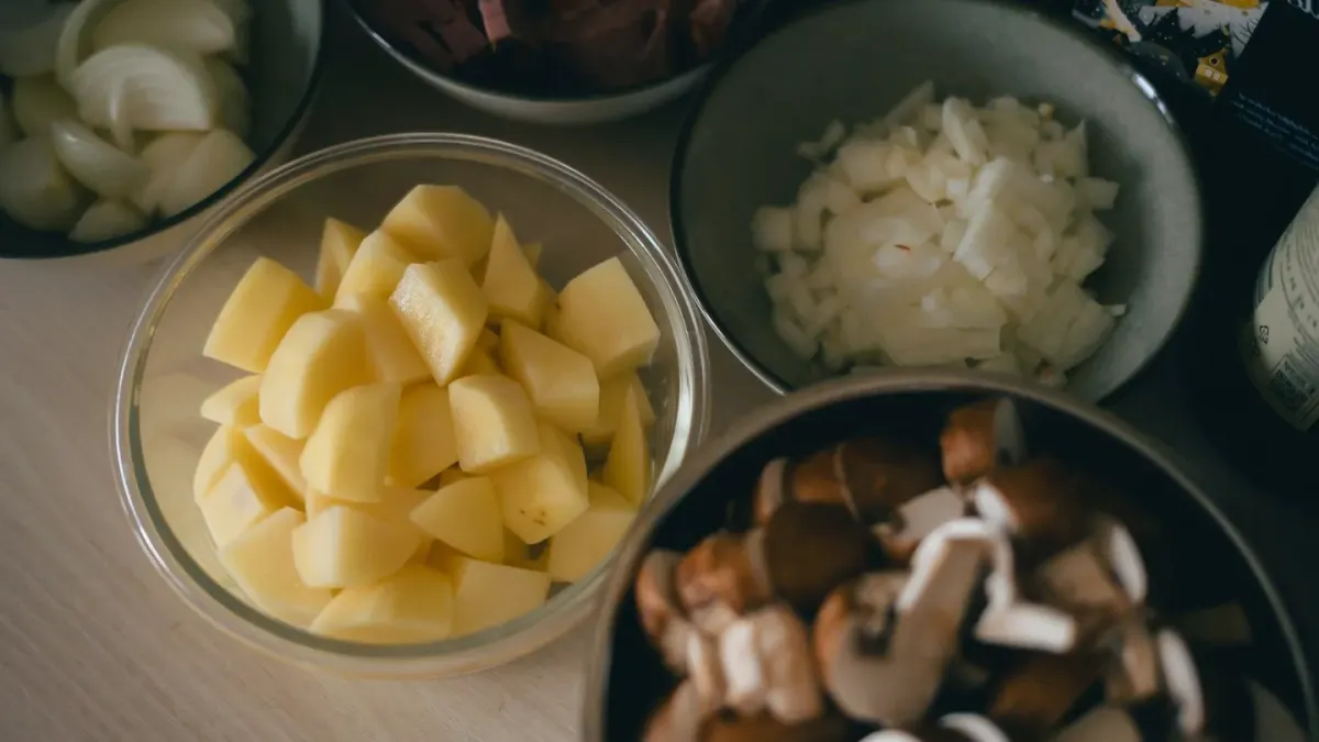 Sliced sweet potato cubes beside a stainless steel bowl of dog kibble on a kitchen counter